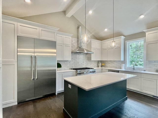 kitchen with white cabinetry, hanging light fixtures, light stone counters, premium appliances, and wall chimney exhaust hood