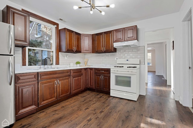 kitchen featuring gas range gas stove, sink, dark hardwood / wood-style flooring, stainless steel fridge, and a chandelier