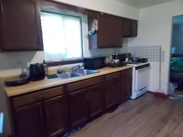 kitchen with tasteful backsplash, sink, dark hardwood / wood-style flooring, white range with electric cooktop, and dark brown cabinets