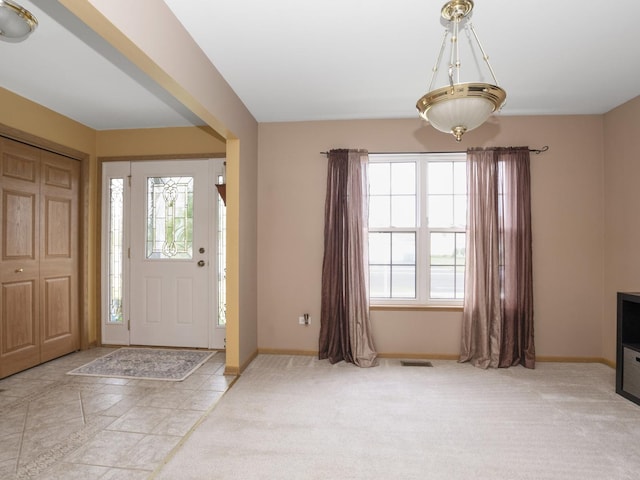 entryway with light colored carpet, visible vents, and baseboards