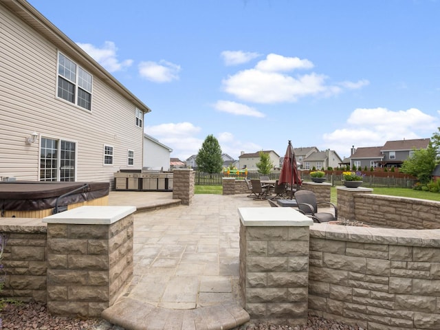 view of patio with a hot tub, a residential view, fence, and an outdoor kitchen