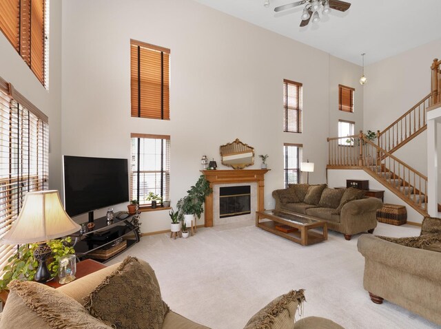 carpeted living room with ceiling fan and a towering ceiling