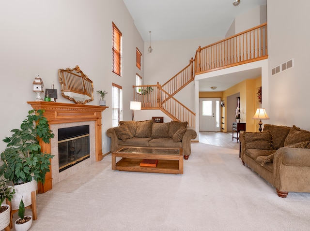 living room featuring a tile fireplace, carpet, and a high ceiling