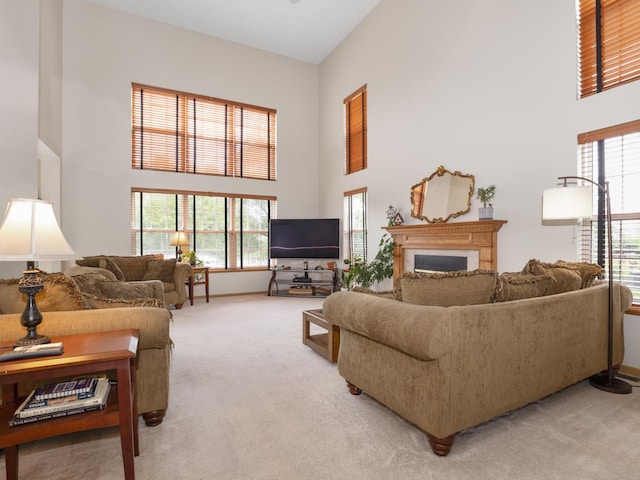 living room with a towering ceiling, a fireplace, and light colored carpet