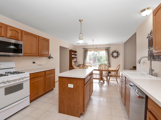 kitchen with appliances with stainless steel finishes, light tile patterned floors, a center island, decorative light fixtures, and sink