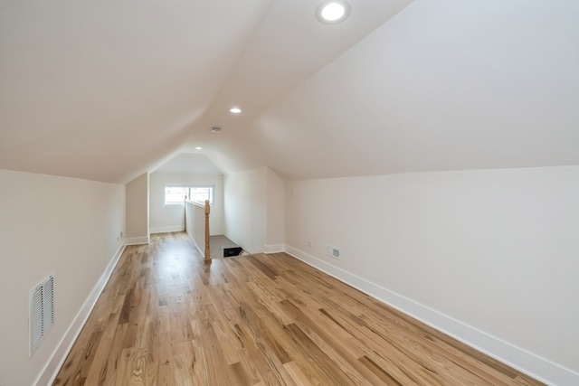 additional living space with light hardwood / wood-style flooring and lofted ceiling