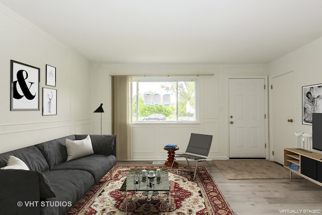 living room with wood finished floors and a decorative wall