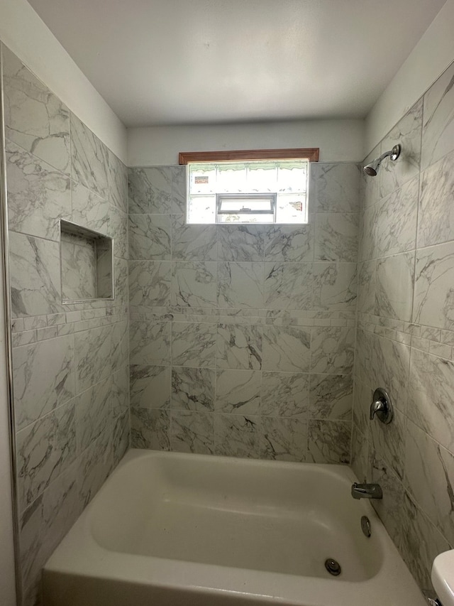 bathroom with toilet and tiled shower / bath