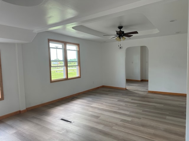 unfurnished room featuring a tray ceiling, light hardwood / wood-style flooring, and ceiling fan