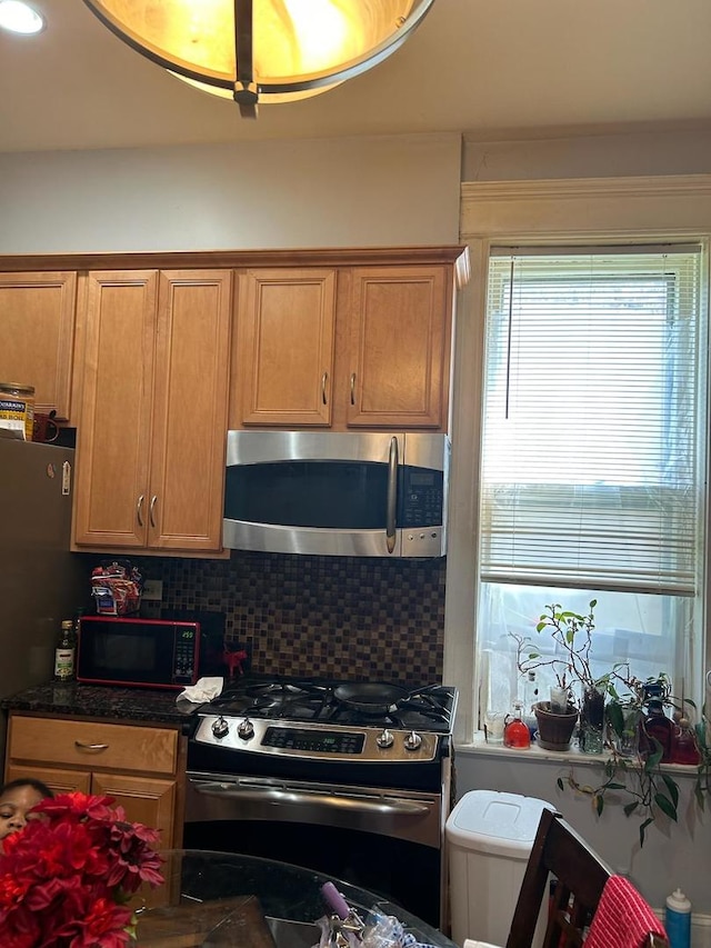 kitchen featuring decorative backsplash, stainless steel appliances, and dark stone countertops