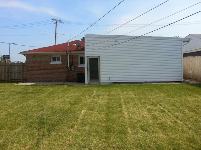 rear view of house with central AC and a yard