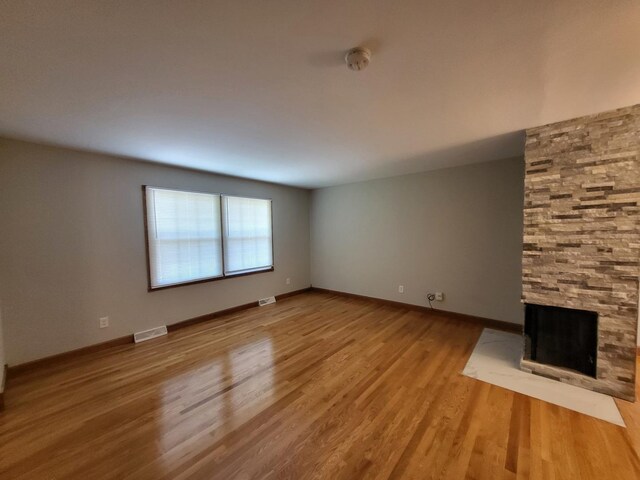 unfurnished living room featuring a multi sided fireplace and hardwood / wood-style floors