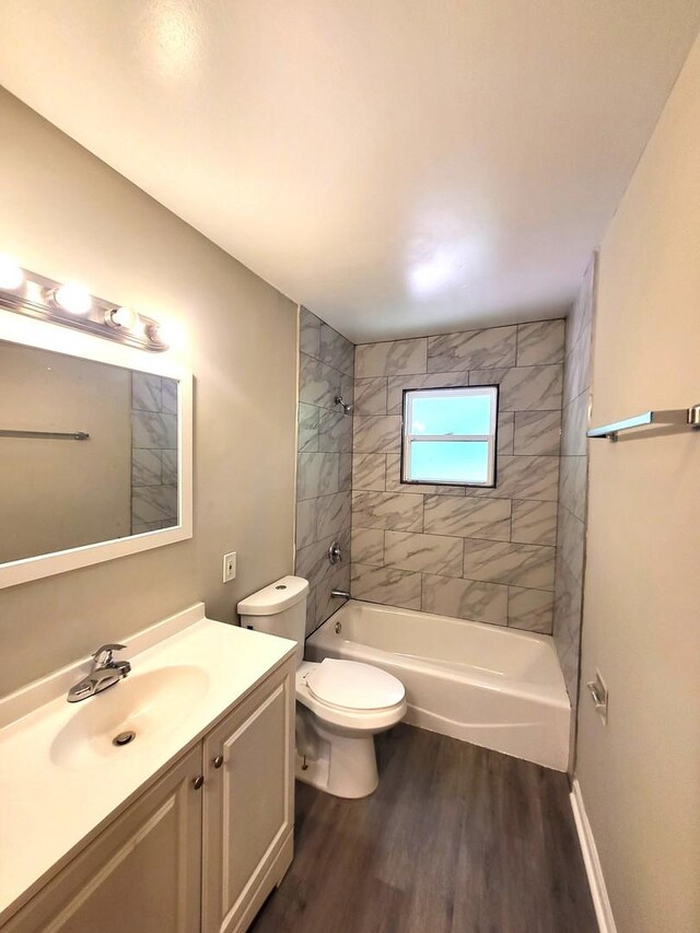 full bathroom with hardwood / wood-style flooring, toilet, tiled shower / bath combo, and vanity