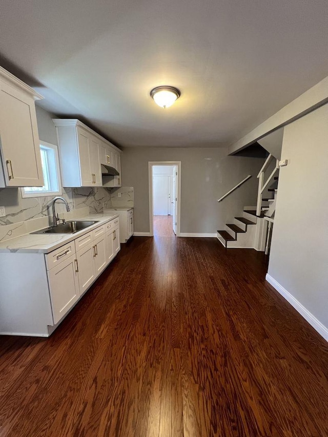 kitchen featuring dark wood-style floors, tasteful backsplash, light countertops, white cabinetry, and a sink