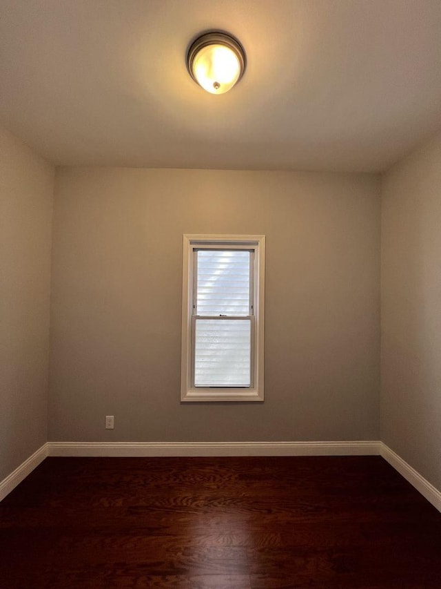 spare room with dark wood-style floors and baseboards