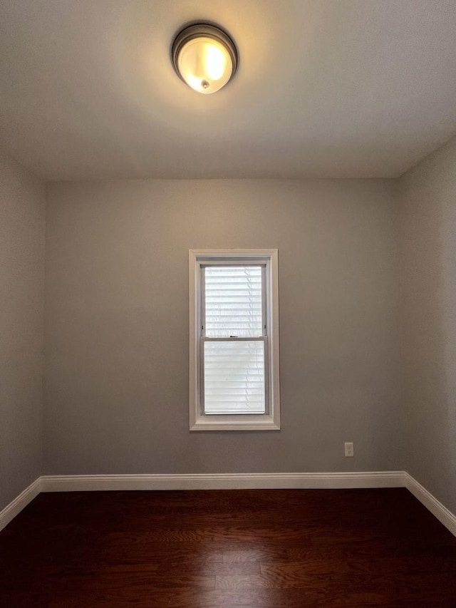 spare room featuring dark wood finished floors and baseboards