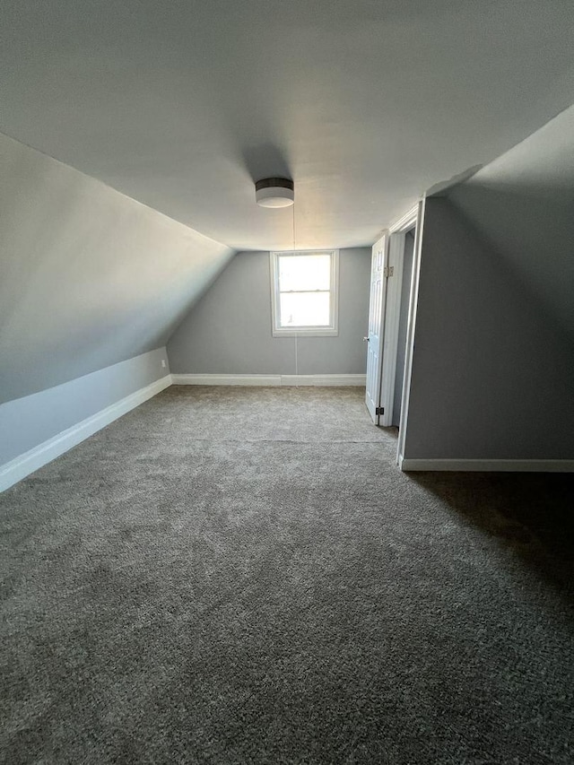 additional living space with carpet flooring, vaulted ceiling, and baseboards