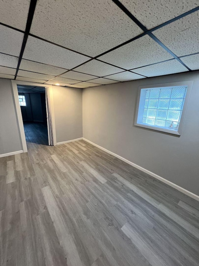 basement featuring a drop ceiling, wood finished floors, and baseboards