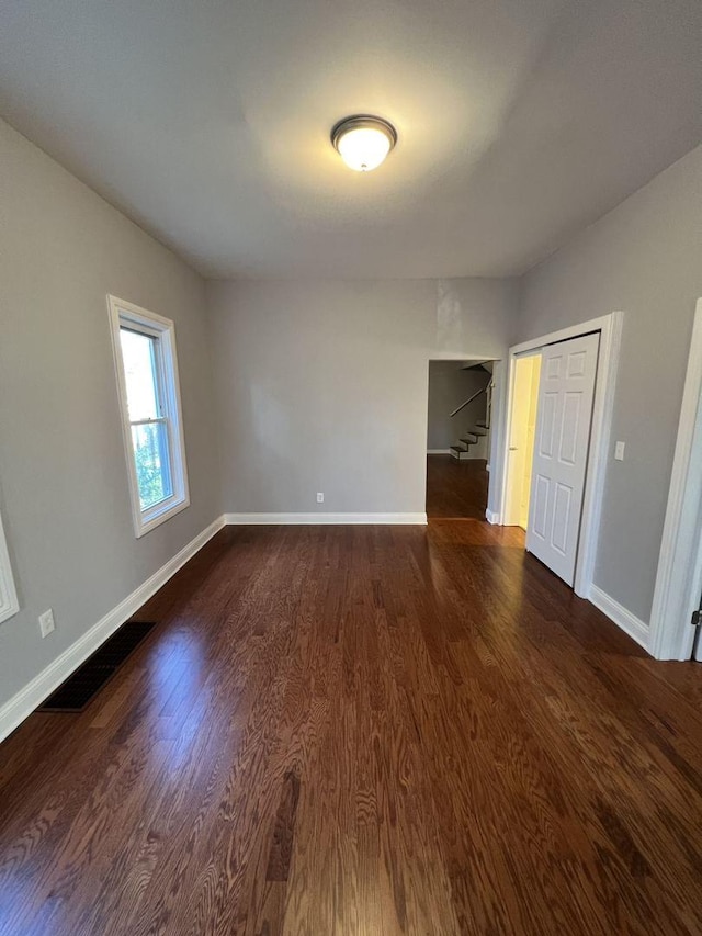 unfurnished bedroom featuring baseboards, visible vents, and dark wood-type flooring