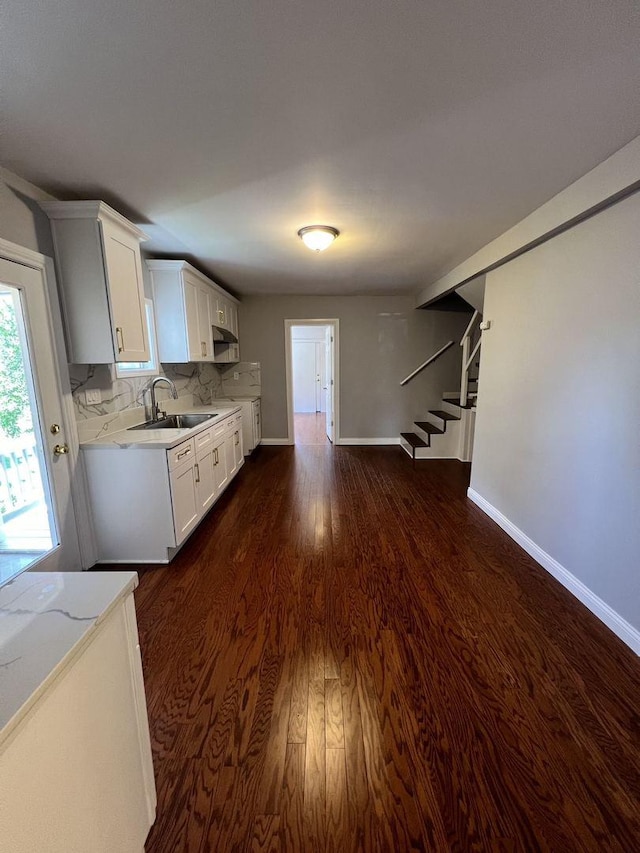 kitchen featuring a sink, baseboards, white cabinets, tasteful backsplash, and dark wood finished floors