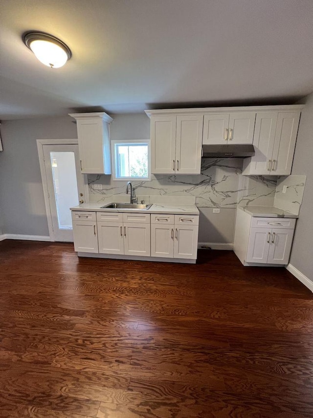 kitchen featuring dark wood-style flooring, a sink, white cabinetry, light countertops, and tasteful backsplash