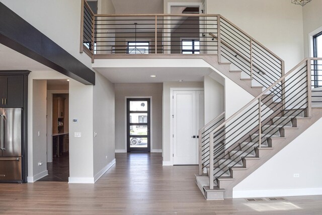 foyer entrance with dark hardwood / wood-style floors and a towering ceiling