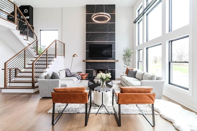 living room featuring stairs, a wealth of natural light, a premium fireplace, and wood finished floors