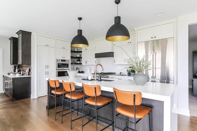 kitchen with a kitchen island, white cabinets, light countertops, hanging light fixtures, and appliances with stainless steel finishes