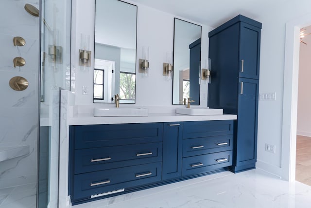 bathroom featuring marble finish floor, a sink, a marble finish shower, and double vanity