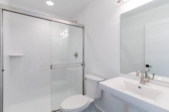 full bath featuring toilet, a shower stall, and a sink