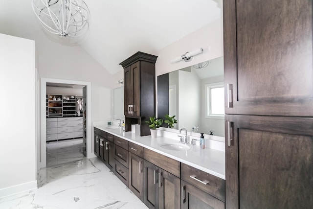 bathroom with lofted ceiling, marble finish floor, a spacious closet, and a sink