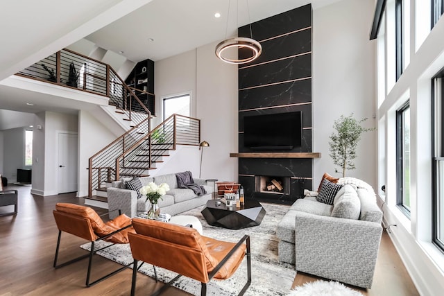 living area with stairs, a high end fireplace, a towering ceiling, and wood finished floors