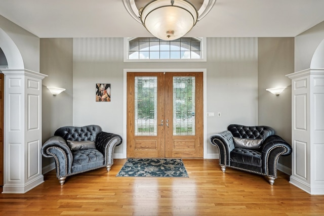 entryway with decorative columns, french doors, and light wood-type flooring