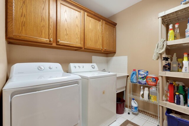 laundry room with washing machine and dryer, cabinets, and light tile patterned floors