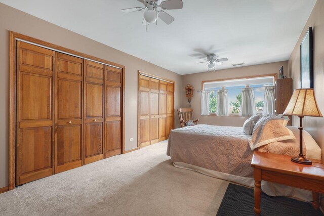 bedroom with multiple closets, carpet flooring, and ceiling fan