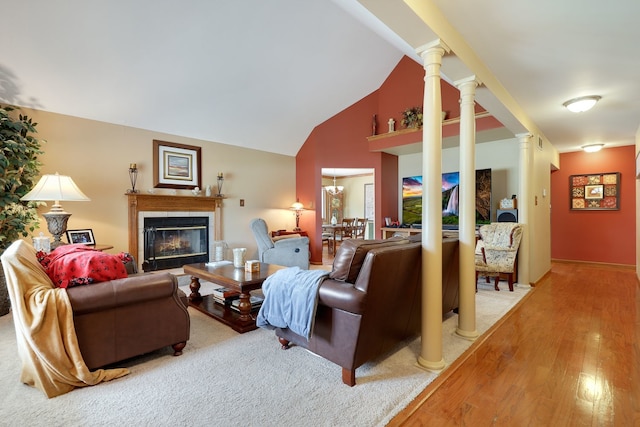 living room featuring decorative columns, light hardwood / wood-style floors, and high vaulted ceiling