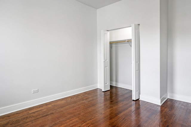 unfurnished bedroom with a closet and dark hardwood / wood-style floors