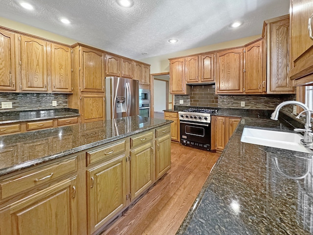 kitchen featuring appliances with stainless steel finishes, light hardwood / wood-style flooring, tasteful backsplash, and sink