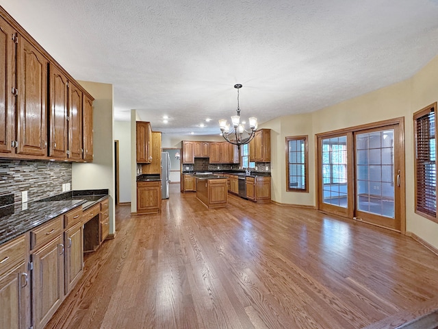 kitchen with pendant lighting, an inviting chandelier, stainless steel appliances, a center island, and hardwood / wood-style floors