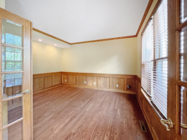 spare room featuring wood-type flooring and crown molding