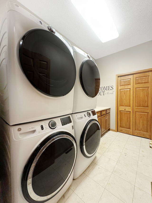 washroom with a textured ceiling, light tile patterned floors, cabinets, washing machine and dryer, and stacked washing maching and dryer