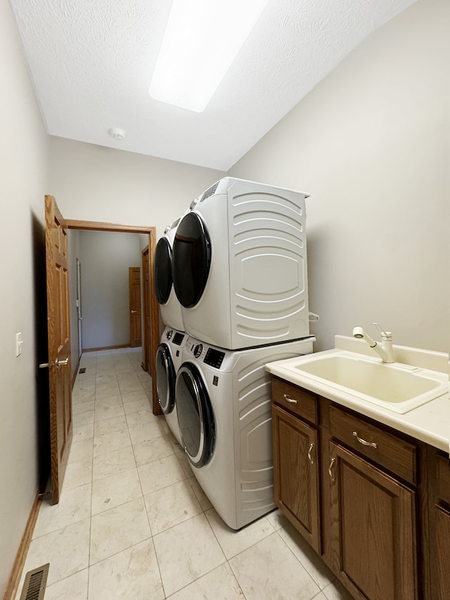 washroom featuring sink, stacked washer / dryer, light tile patterned floors, and cabinets