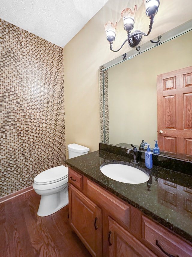 bathroom featuring a textured ceiling, hardwood / wood-style floors, tile walls, toilet, and vanity