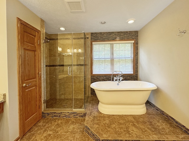 bathroom featuring a textured ceiling, tile patterned flooring, and independent shower and bath