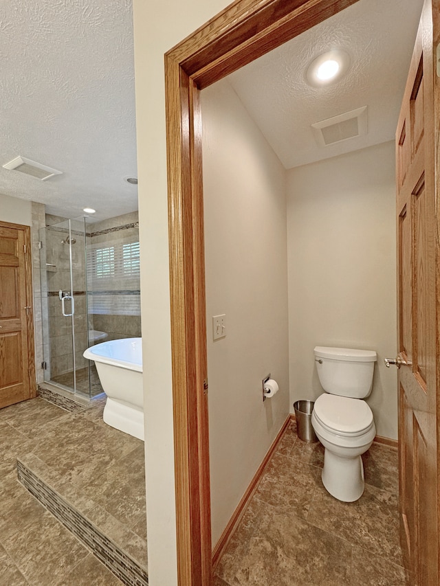 bathroom with plus walk in shower, a textured ceiling, toilet, and tile patterned floors