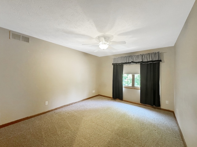 empty room with ceiling fan, a textured ceiling, and carpet flooring