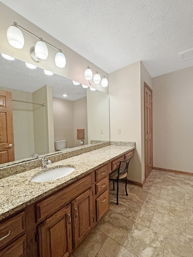 bathroom with a textured ceiling, toilet, tile patterned floors, and vanity