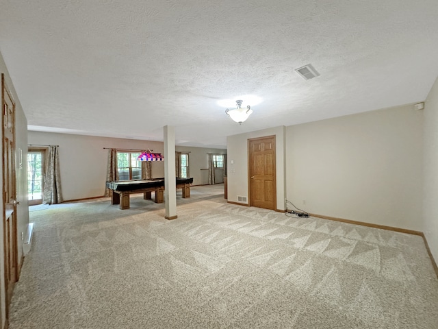 carpeted empty room featuring a textured ceiling and pool table