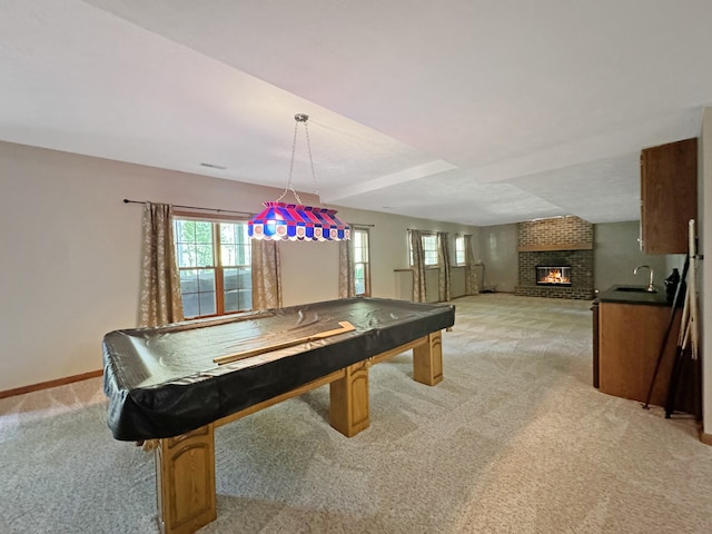 playroom featuring light carpet, brick wall, a brick fireplace, pool table, and sink