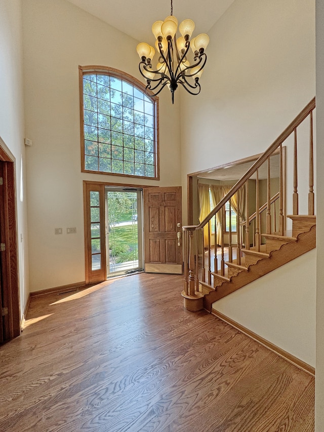 foyer with a notable chandelier, wood-type flooring, and high vaulted ceiling